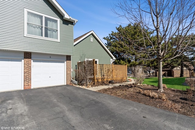 view of property exterior featuring aphalt driveway, brick siding, and an attached garage