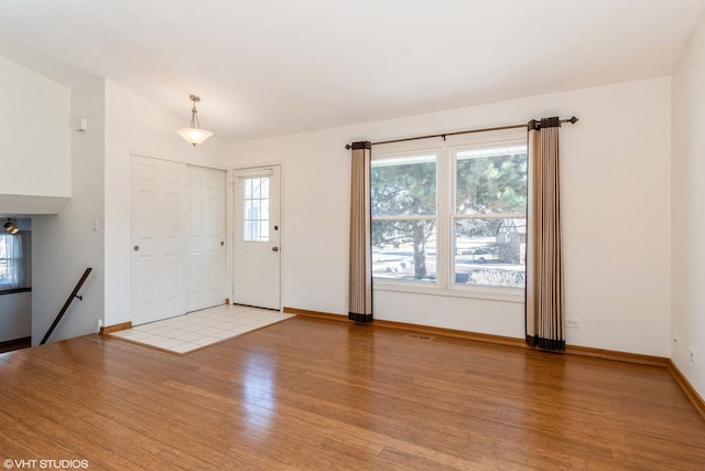 foyer featuring light wood-type flooring, vaulted ceiling, and baseboards