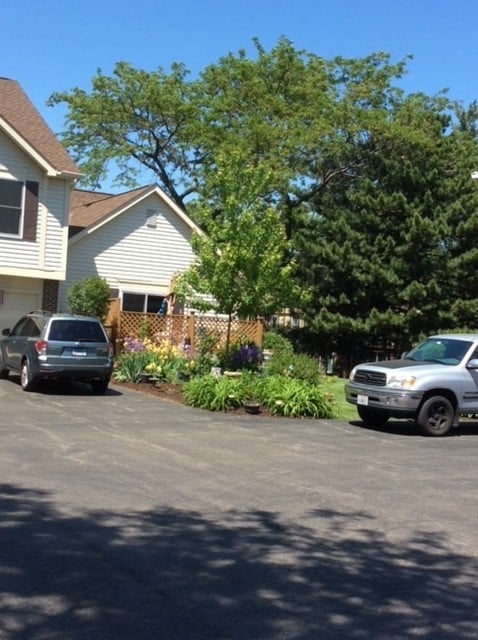 view of parking featuring an attached garage, fence, and aphalt driveway