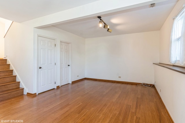 unfurnished room with light wood finished floors, stairway, and baseboards