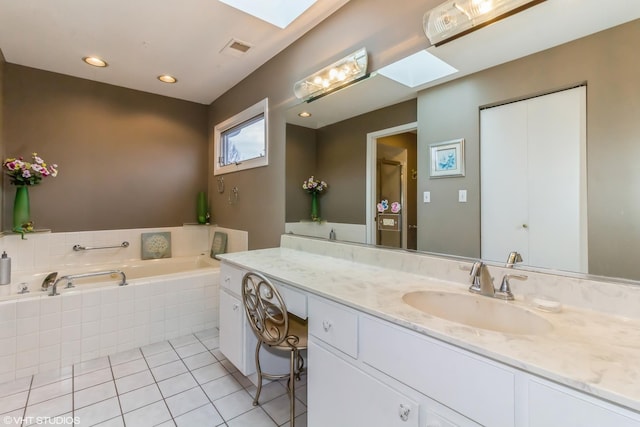 bathroom featuring a skylight, a garden tub, visible vents, vanity, and tile patterned flooring