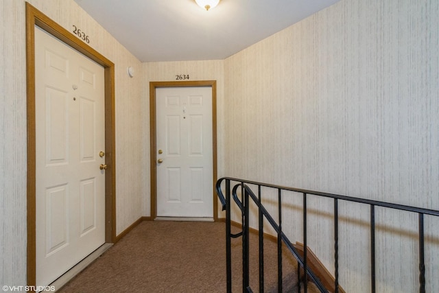 hallway featuring carpet floors, wallpapered walls, and baseboards