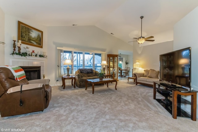 living area with visible vents, a ceiling fan, a tiled fireplace, carpet floors, and high vaulted ceiling