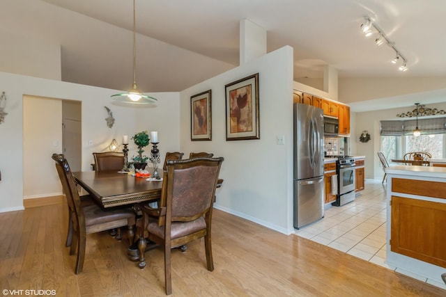 dining space featuring lofted ceiling, light wood-style floors, baseboards, and track lighting