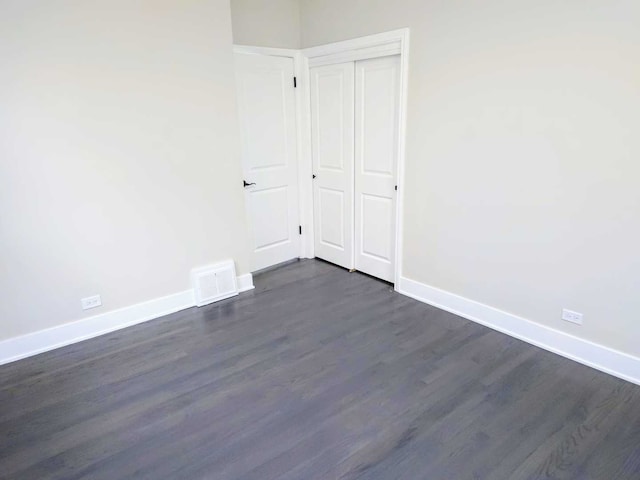 empty room featuring visible vents, dark wood finished floors, and baseboards