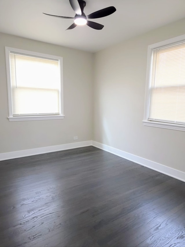 spare room featuring a ceiling fan, dark wood-style flooring, and baseboards