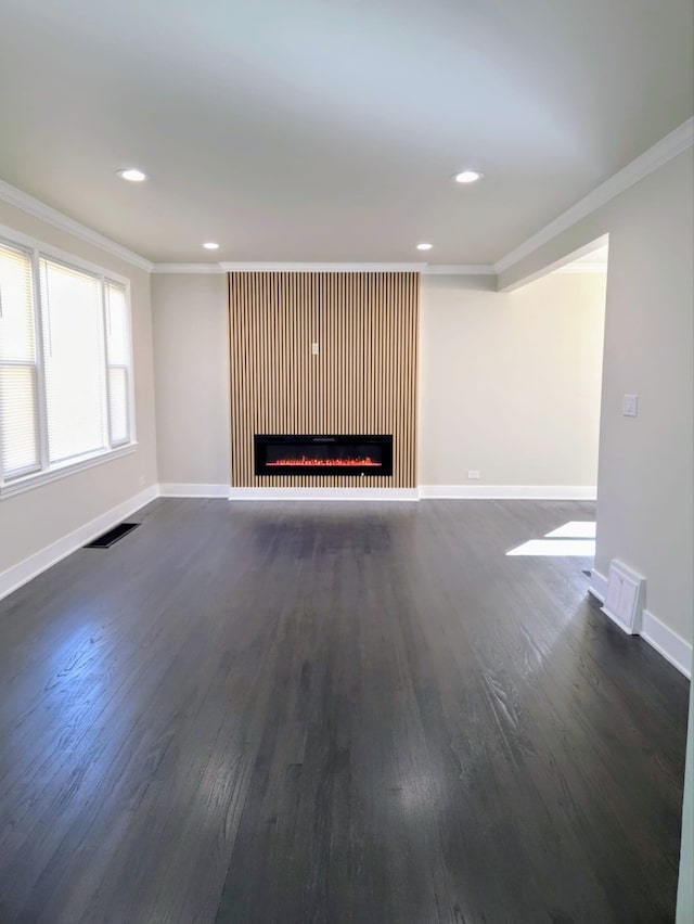 unfurnished living room with dark wood-style floors, visible vents, baseboards, and crown molding