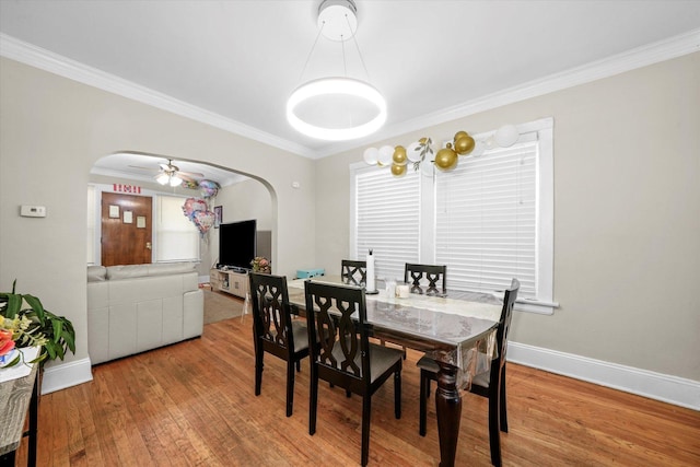 dining area featuring ornamental molding, arched walkways, and hardwood / wood-style floors