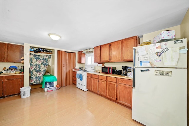 kitchen featuring light countertops, white appliances, brown cabinetry, and light wood-style floors