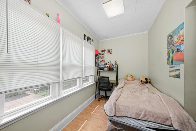 bedroom with ornamental molding, light wood finished floors, and baseboards