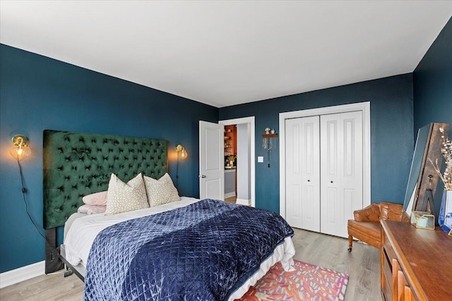 bedroom featuring a closet, light wood-style flooring, and baseboards