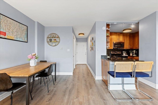 kitchen featuring stainless steel appliances, light wood finished floors, backsplash, and baseboards