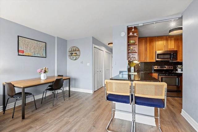 kitchen with backsplash, stainless steel appliances, light wood-type flooring, open shelves, and a sink