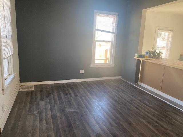 unfurnished room with visible vents, baseboards, and dark wood-type flooring