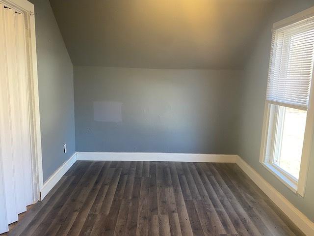 bonus room featuring lofted ceiling, dark wood-style flooring, and baseboards