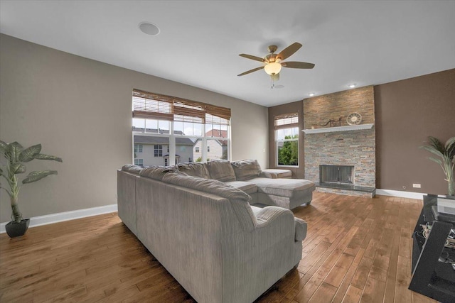 living room with a fireplace, wood finished floors, a ceiling fan, and baseboards