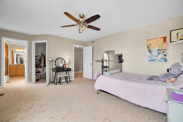 carpeted bedroom with baseboards, connected bathroom, visible vents, and a ceiling fan