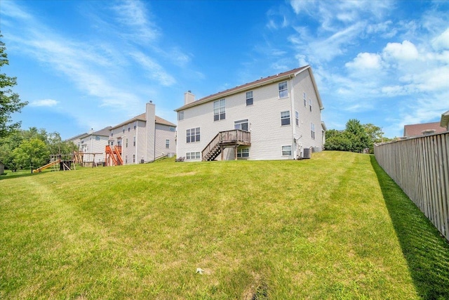 rear view of house featuring a yard, a chimney, central AC unit, fence, and stairs