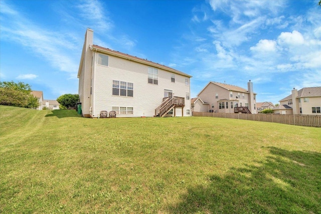 back of house with a yard, stairway, a chimney, and fence