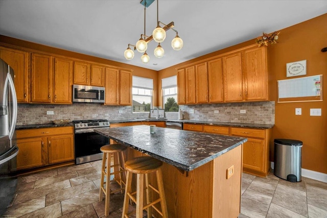 kitchen featuring a center island, stainless steel appliances, backsplash, brown cabinetry, and a kitchen bar