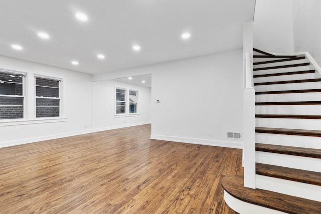 unfurnished living room with recessed lighting, visible vents, stairway, wood finished floors, and baseboards