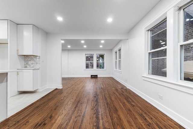 unfurnished living room with recessed lighting, wood finished floors, and baseboards