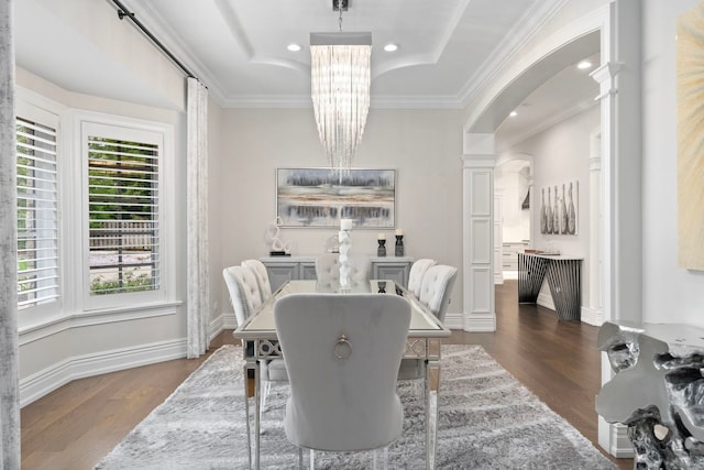 dining room with arched walkways, dark wood finished floors, ornamental molding, ornate columns, and a notable chandelier