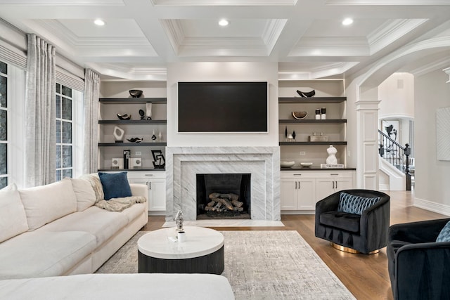 living room with arched walkways, coffered ceiling, and beamed ceiling