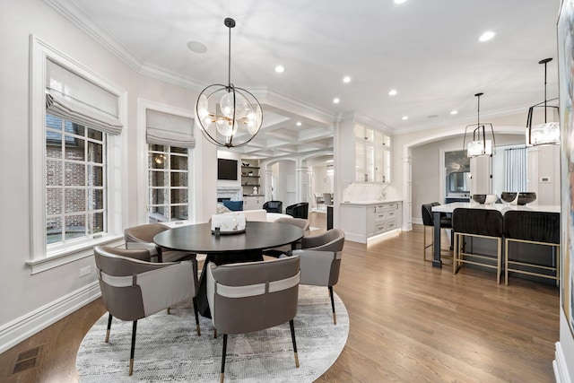 dining area featuring arched walkways, wood finished floors, visible vents, and crown molding