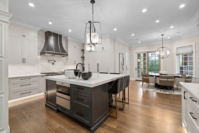 kitchen featuring ornamental molding, white cabinetry, wall chimney range hood, and dark wood-type flooring