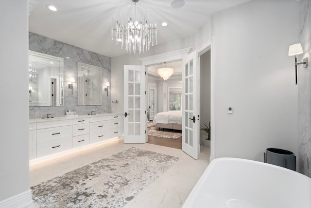 ensuite bathroom with ensuite bathroom, a freestanding tub, a notable chandelier, marble finish floor, and french doors