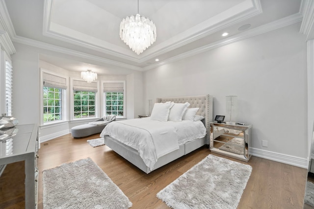 bedroom featuring a chandelier, a raised ceiling, baseboards, and wood finished floors