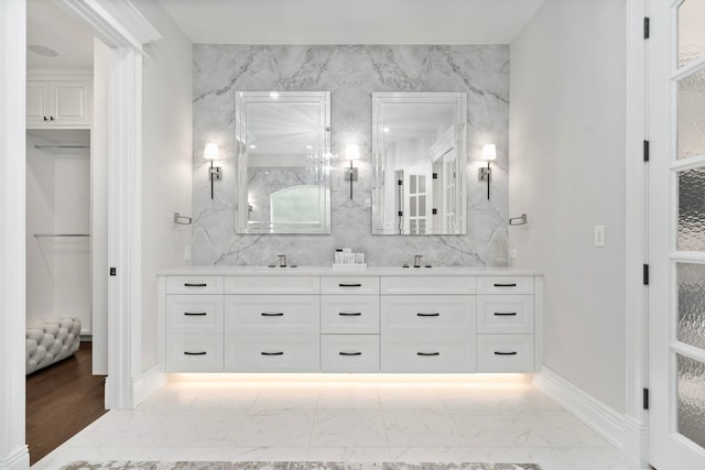 bathroom with marble finish floor, double vanity, and a sink