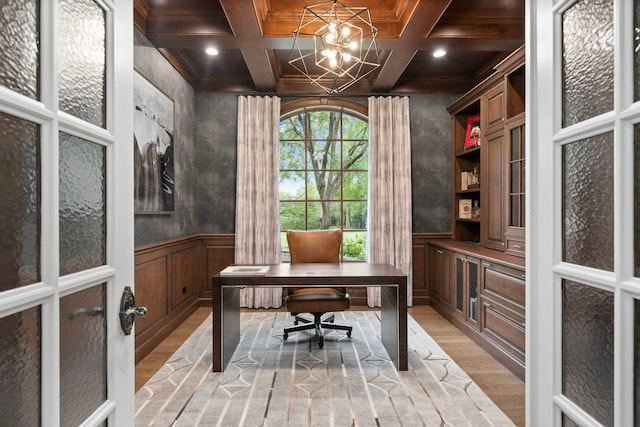 office space featuring light wood-style floors, beam ceiling, wainscoting, and coffered ceiling