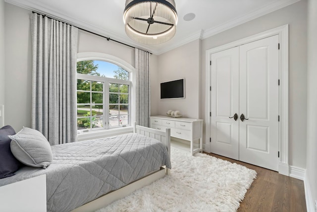 bedroom featuring baseboards, a closet, ornamental molding, and wood finished floors