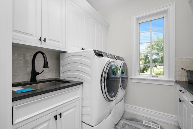 clothes washing area with cabinet space, baseboards, visible vents, washer and clothes dryer, and a sink