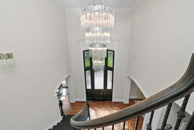 entryway featuring arched walkways, a high ceiling, ornamental molding, and a notable chandelier