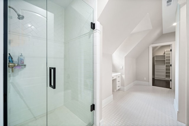 bathroom with lofted ceiling, a walk in closet, and a shower stall