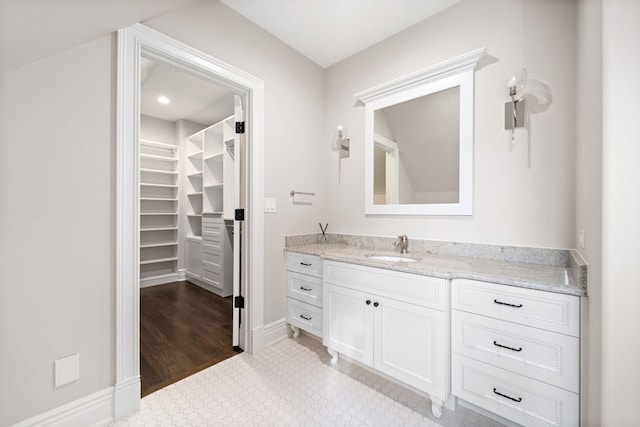 bathroom featuring a walk in closet, vanity, and baseboards