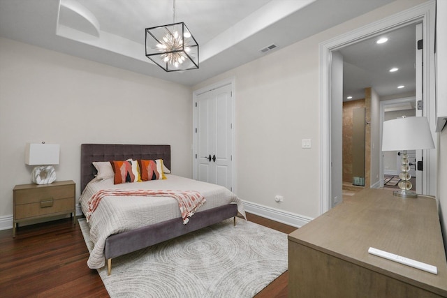 bedroom with a tray ceiling, dark wood finished floors, visible vents, and recessed lighting