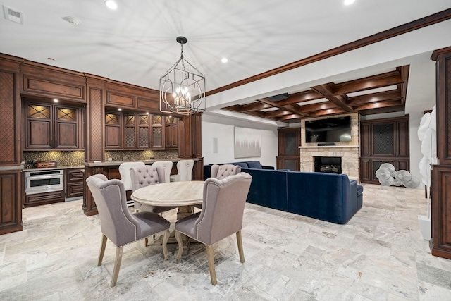 dining room featuring visible vents, ornamental molding, a stone fireplace, coffered ceiling, and beamed ceiling