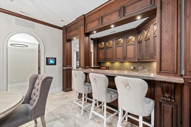 bar featuring arched walkways, visible vents, decorative backsplash, ornamental molding, and baseboards