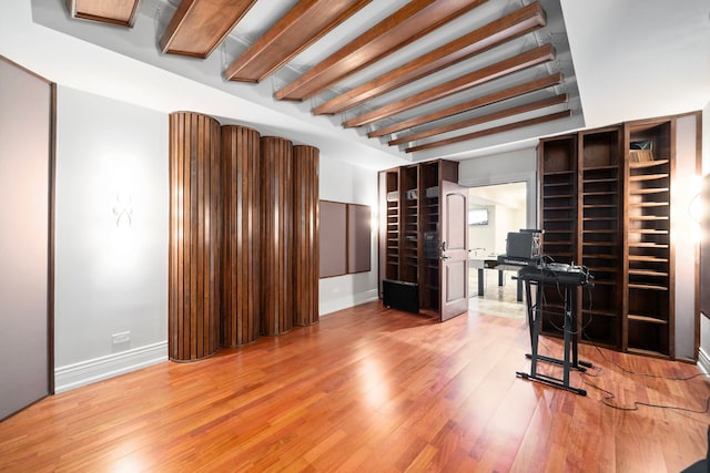 interior space featuring beam ceiling, baseboards, and wood finished floors