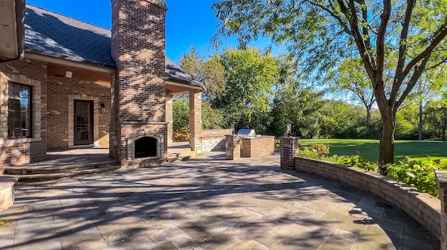 view of patio featuring an outdoor brick fireplace and exterior kitchen