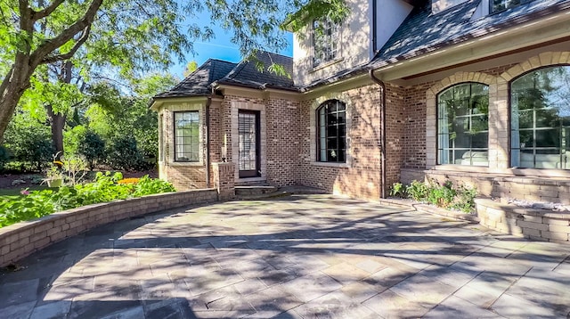 entrance to property with a patio area and brick siding