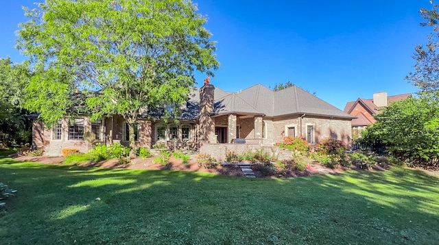 back of house featuring brick siding and a yard