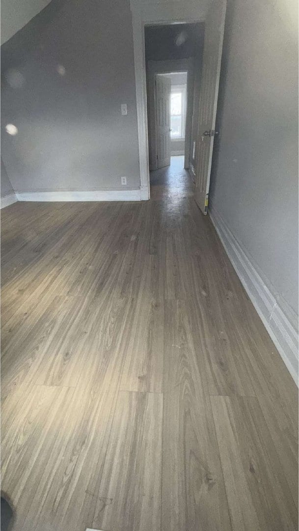 unfurnished room with baseboards and wood finished floors