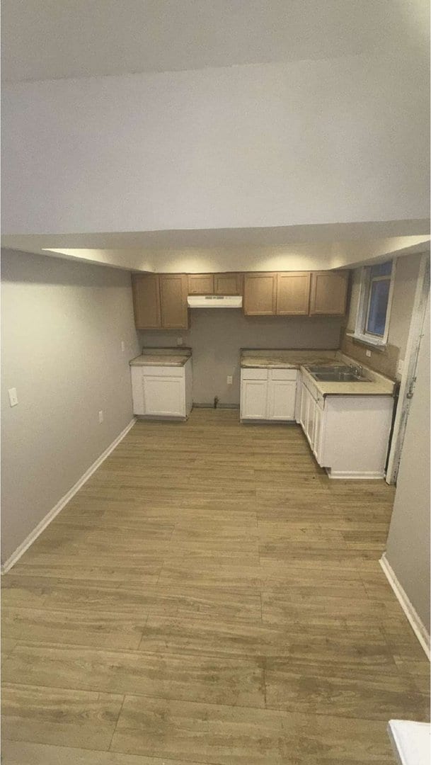 kitchen featuring light wood finished floors, a sink, and baseboards