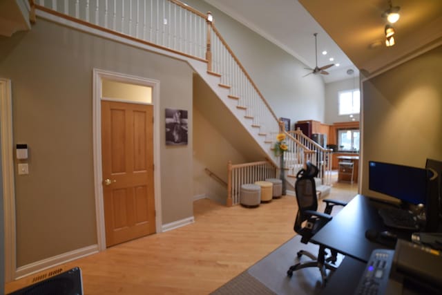 office space with baseboards, ceiling fan, wood finished floors, a high ceiling, and recessed lighting