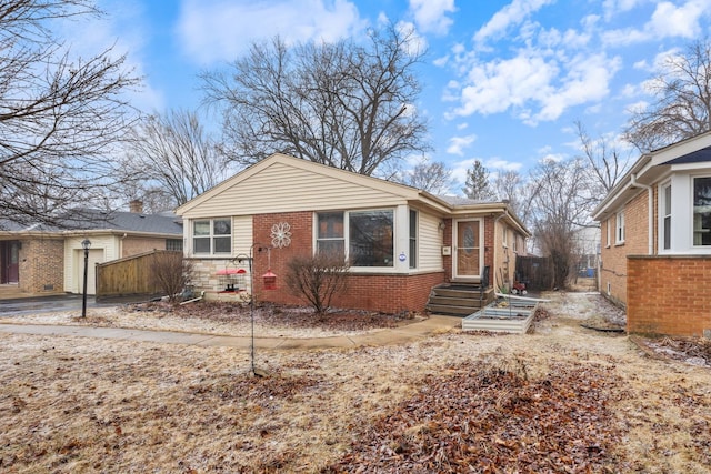 bungalow featuring brick siding and fence